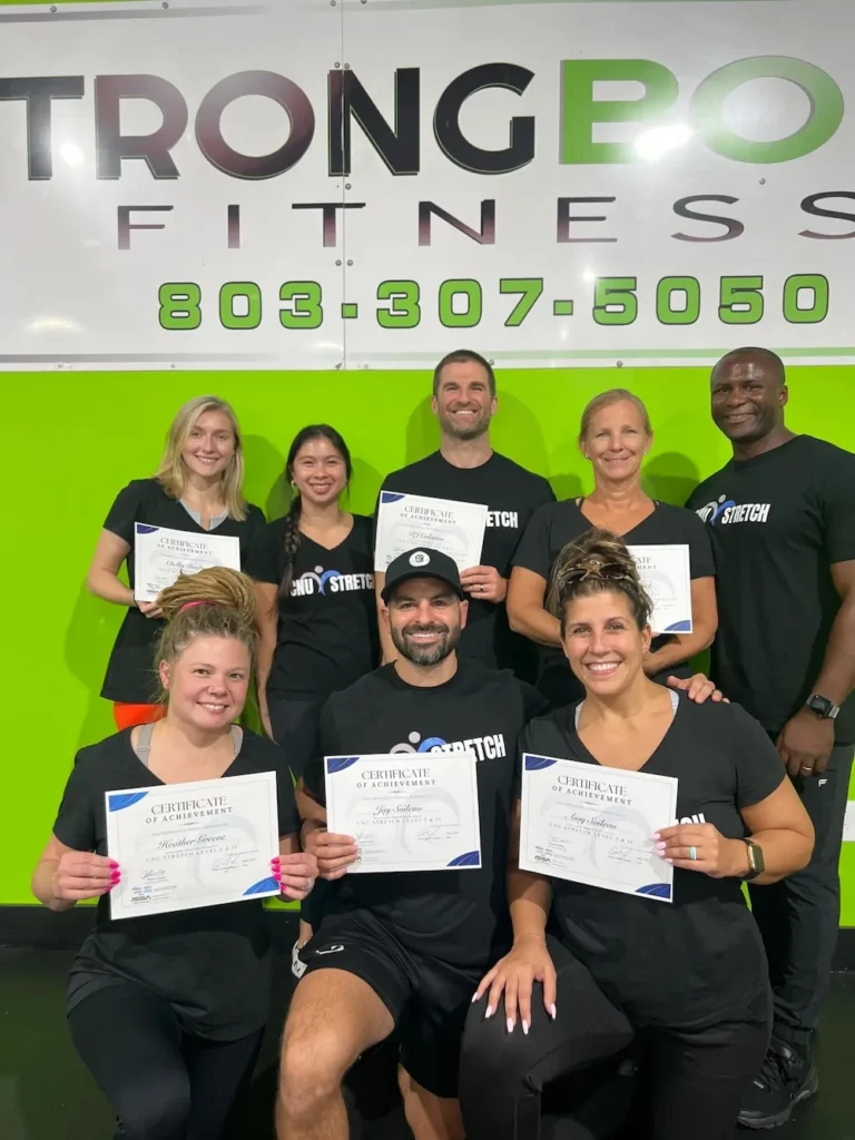 Community health fair scene with gym staff demonstrating stretch therapy techniques to engaged attendees